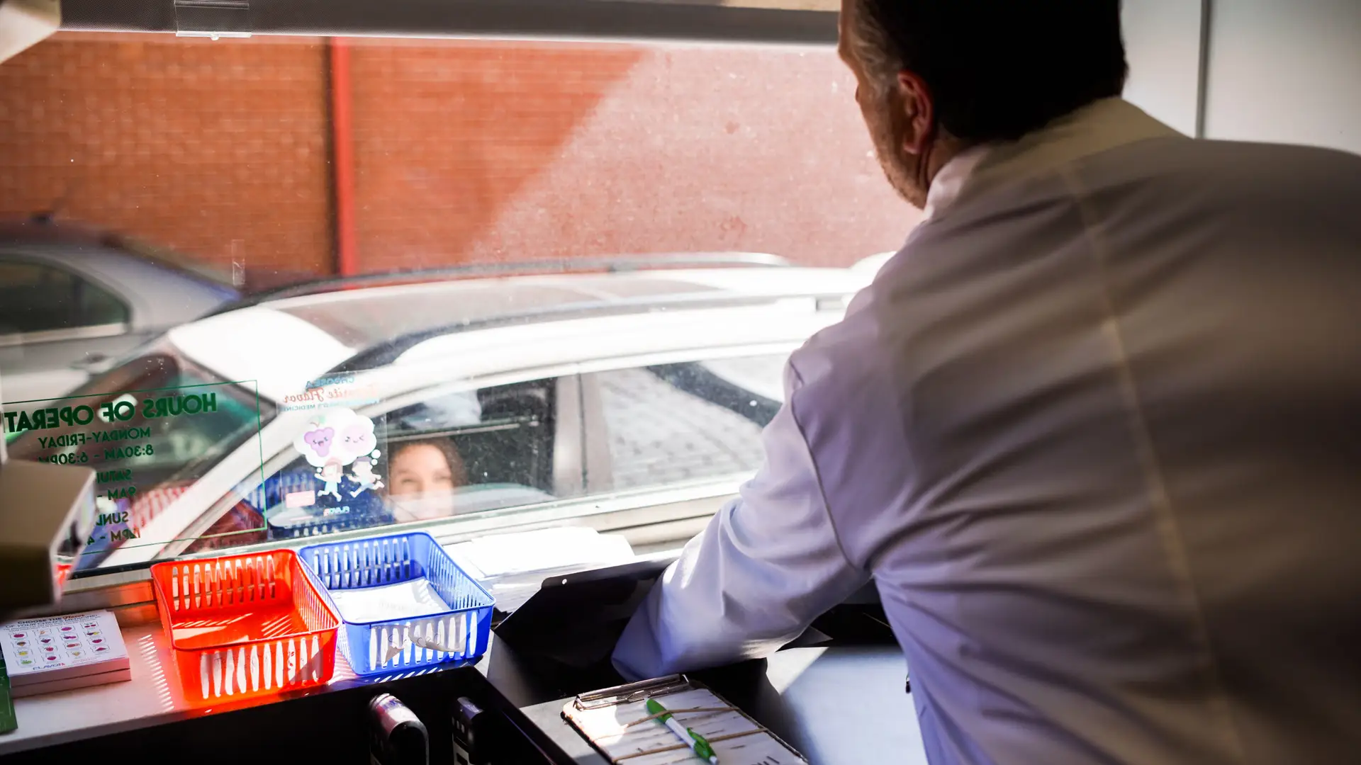 Economy Pharmacy team member handing a prescription to a patient at the drive-thru window